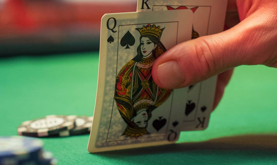 Person holding two cards at a blackjack table
